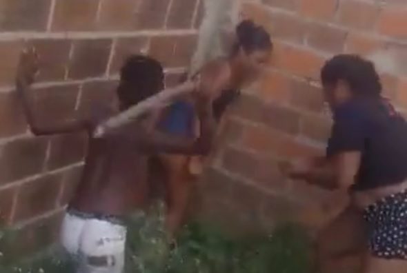 Woman being beaten by a child and another woman with sticks.