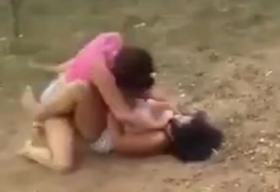 Women fight on the dirt floor to see who is the strongest.