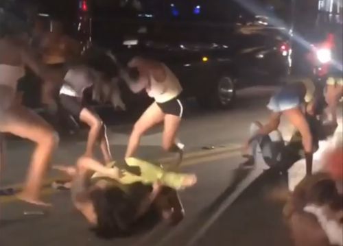 A bunch of women fighting in the middle of the street.