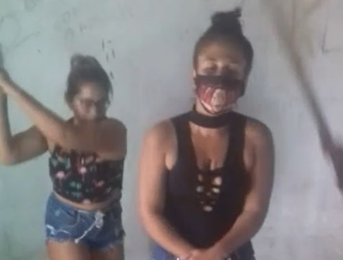 Women apply favela’s law to educate another woman with wooden blows.