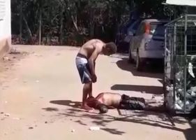 Man being stoned and stomped to death by a mad man in broad daylight.