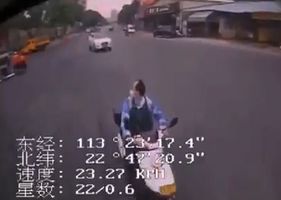 In China, a man has a heart attack, falls off his motorcycle and hits the ground.
